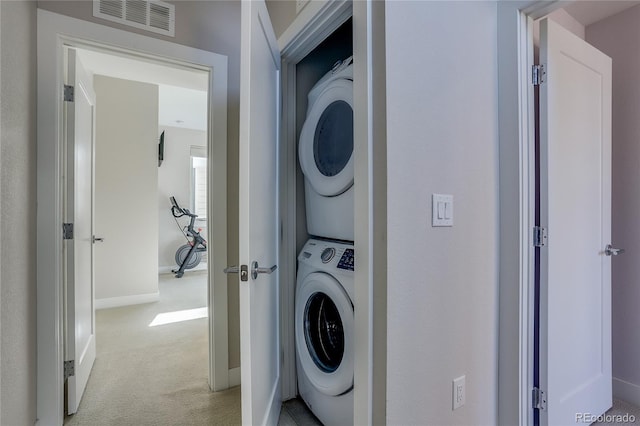 laundry room with stacked washing maching and dryer and light colored carpet