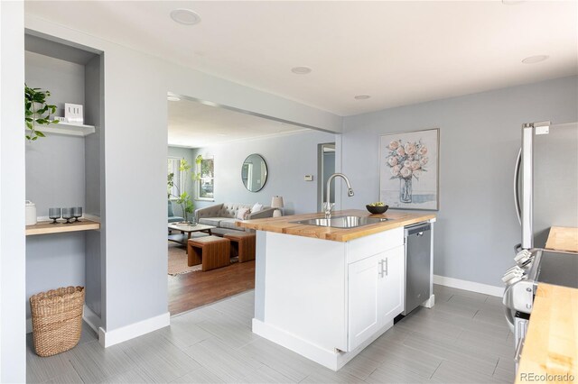 8240 Grandview Ave, Arvada, CO 80002 - kitchen featuring wood counters, a sink, appliances with stainless steel finishes, open floor plan, and white cabinetry