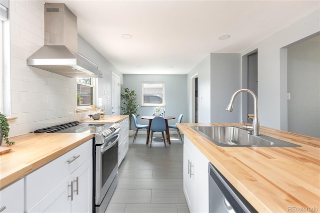 8240 Grandview Ave, Arvada, CO 80002 - kitchen featuring butcher block counters, stainless steel appliances, wall chimney exhaust hood, a sink, and backsplash