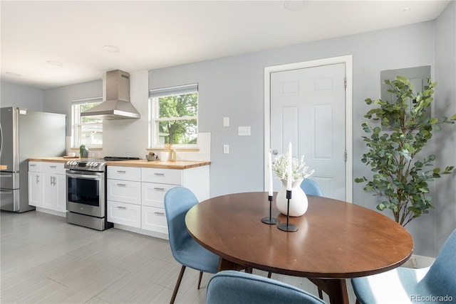 8240 Grandview Ave, Arvada, CO 80002 - kitchen featuring island exhaust hood, wooden counters, appliances with stainless steel finishes, white cabinetry, and tasteful backsplash