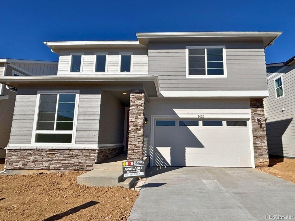 view of front of property with an attached garage, stone siding, and concrete driveway
