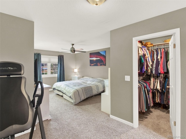 bedroom with a spacious closet, baseboards, a closet, and light colored carpet