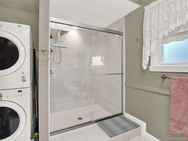 full bath featuring stacked washer / drying machine, a stall shower, and tile patterned flooring