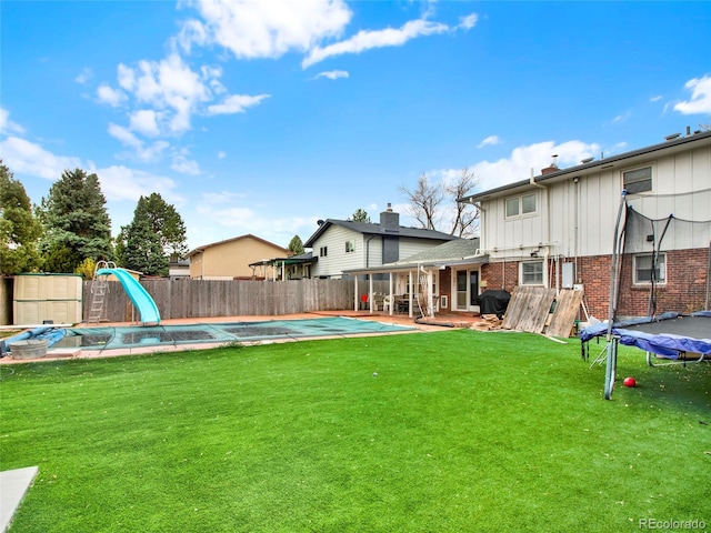 view of yard featuring a trampoline, a fenced backyard, and a fenced in pool