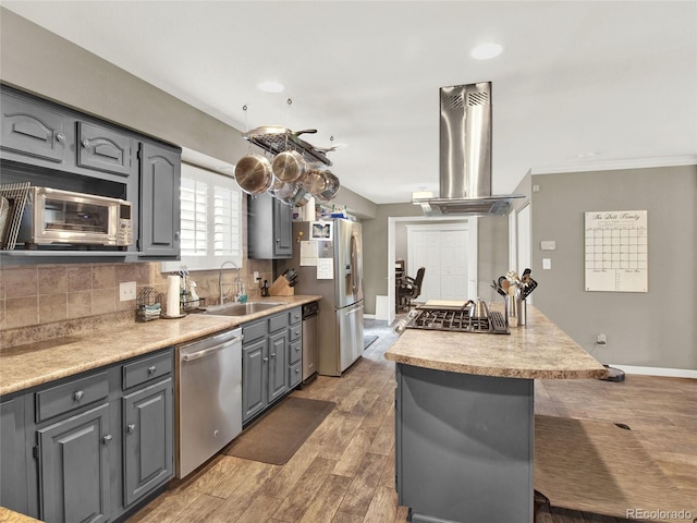 kitchen featuring backsplash, a sink, gray cabinetry, stainless steel appliances, and island range hood