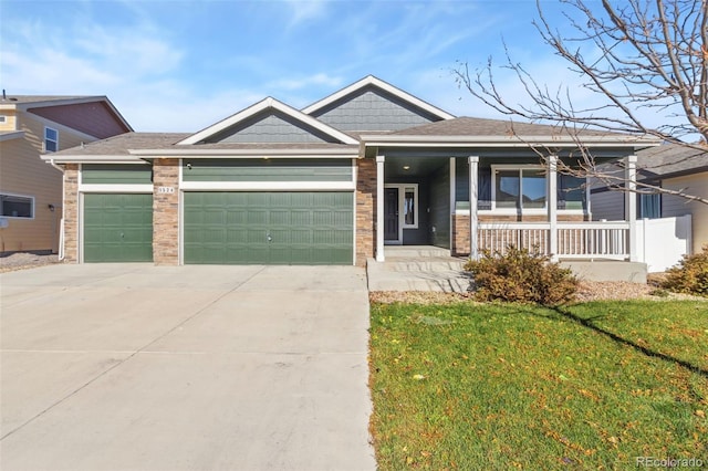 view of front of home featuring covered porch, a garage, and a front yard