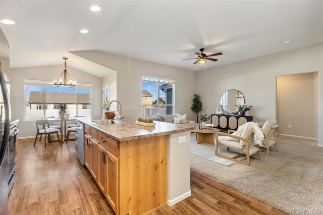 kitchen featuring a healthy amount of sunlight, light hardwood / wood-style floors, an island with sink, and hanging light fixtures