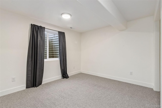 carpeted empty room featuring beamed ceiling