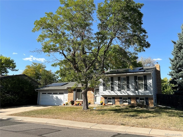 view of front of house featuring a garage, solar panels, and a front lawn