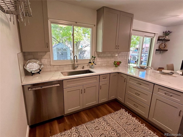 kitchen with a wealth of natural light, sink, dark wood-type flooring, and stainless steel dishwasher