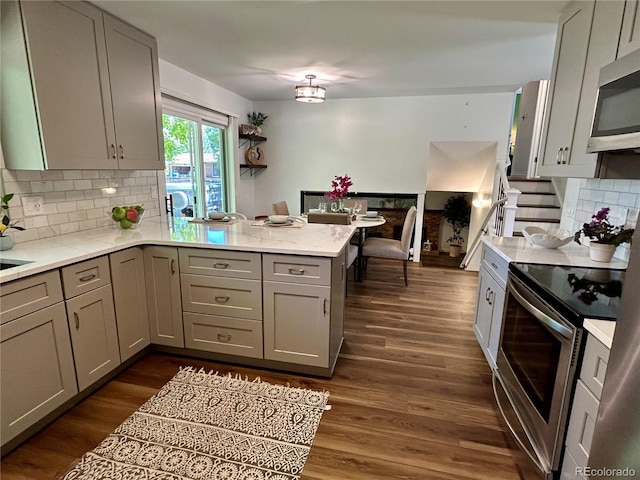 kitchen with appliances with stainless steel finishes, kitchen peninsula, and gray cabinets