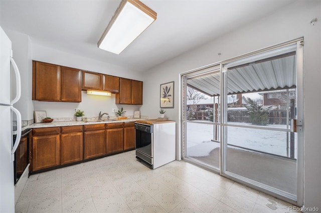 kitchen featuring dishwashing machine, white fridge, and sink