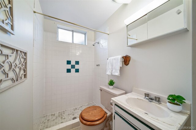 bathroom featuring tiled shower, vanity, and toilet