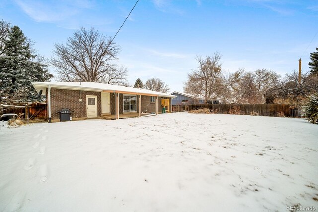 view of snow covered back of property