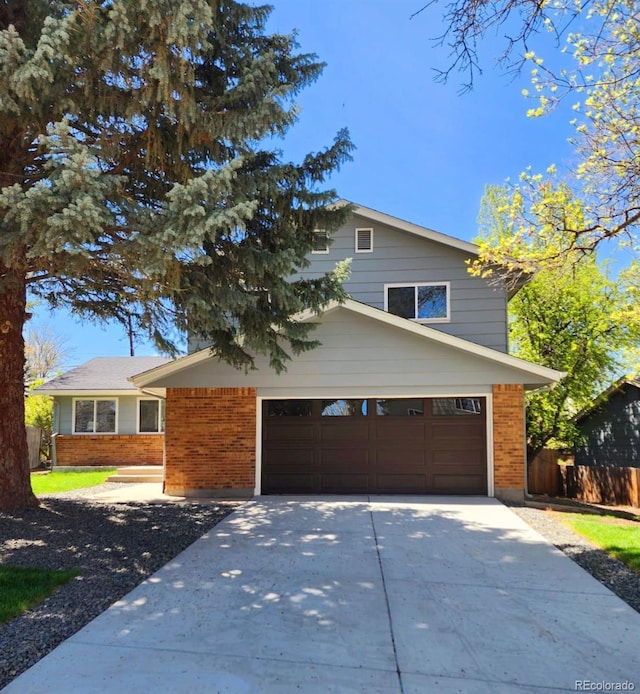 view of front of home with brick siding, driveway, fence, and a garage