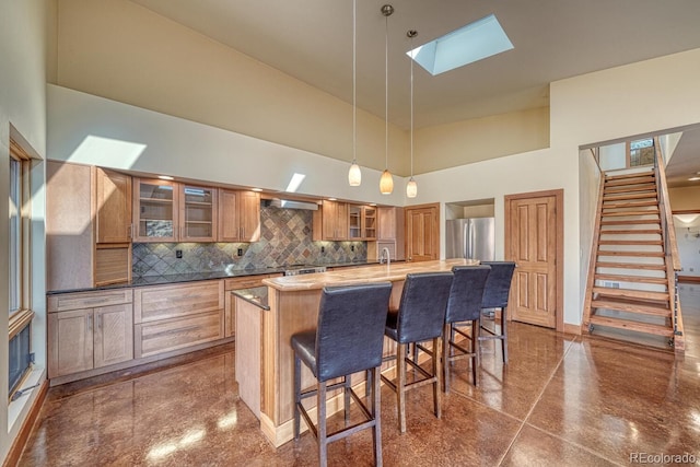 10405 W Cherokee Dr, Salida, CO 81201 - kitchen with freestanding refrigerator, a towering ceiling, a skylight, decorative backsplash, and an island with sink