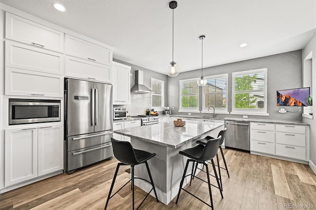 15547 W Vassar Ave, Lakewood, CO 80228 - kitchen featuring stainless steel appliances, wall chimney range hood, white cabinets, light stone countertops, and tasteful backsplash
