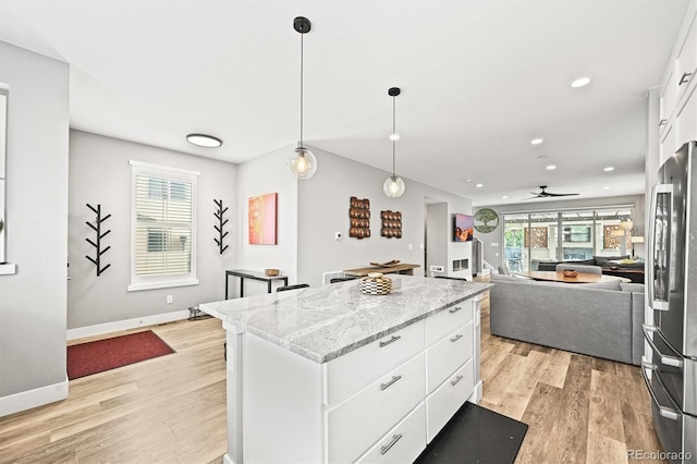 15547 W Vassar Ave, Lakewood, CO 80228 - kitchen with stainless steel refrigerator, light wood-type flooring, white cabinetry, a kitchen island, and open floor plan