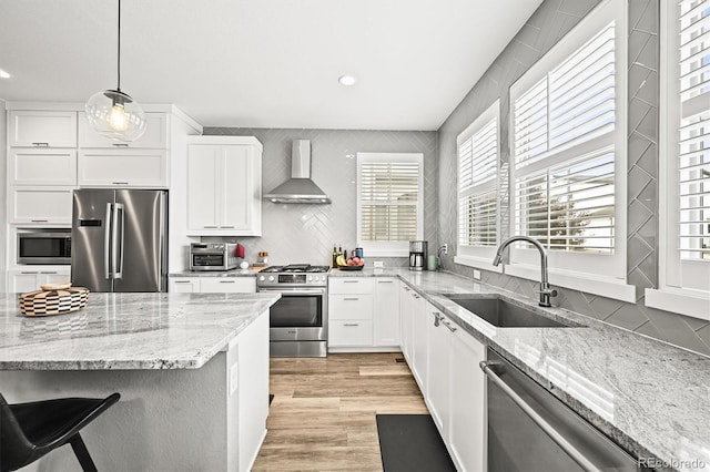 15547 W Vassar Ave, Lakewood, CO 80228 - kitchen with appliances with stainless steel finishes, wall chimney exhaust hood, white cabinets, healthy amount of natural light, and recessed lighting