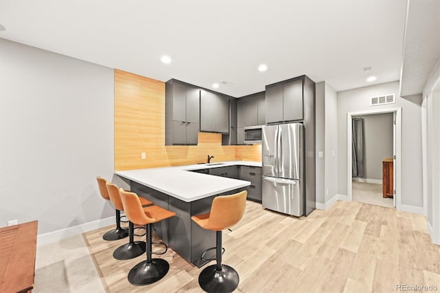 15547 W Vassar Ave, Lakewood, CO 80228 - kitchen with stainless steel appliances, a peninsula, a breakfast bar area, backsplash, and light countertops