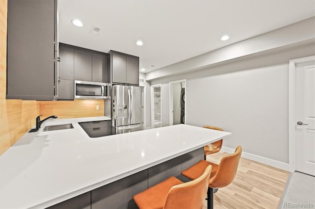 15547 W Vassar Ave, Lakewood, CO 80228 - kitchen featuring stainless steel appliances, a peninsula, a breakfast bar area, decorative backsplash, and recessed lighting