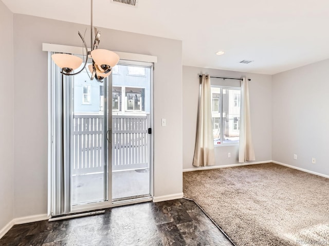 entryway with plenty of natural light, a chandelier, and dark colored carpet