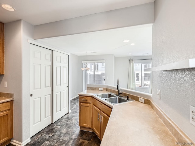 5888 Biscay St Unit D, Denver, CO 80249 - kitchen with a sink, a peninsula, light countertops, brown cabinets, and hanging light fixtures