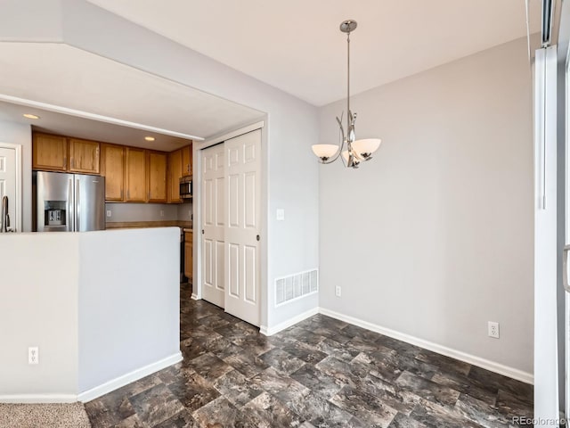 5888 Biscay St Unit D, Denver, CO 80249 - kitchen with stainless steel appliances, brown cabinetry, a chandelier, and baseboards
