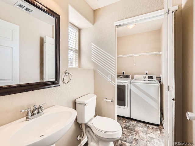 5888 Biscay St Unit D, Denver, CO 80249 - half bath featuring a sink, toilet, washer and dryer, a textured wall, and stone finish flooring