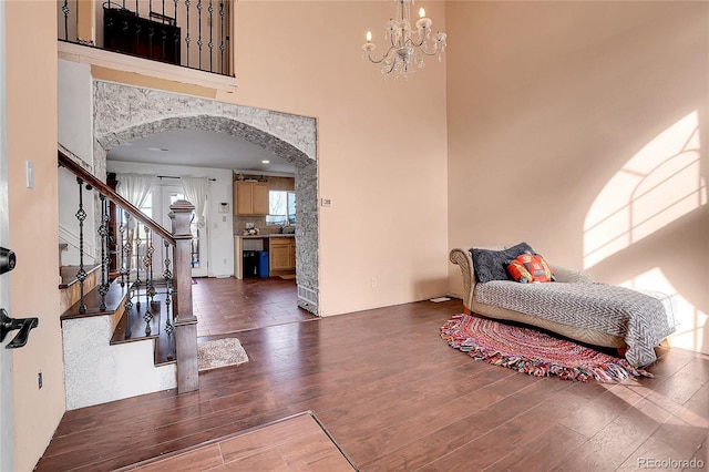 interior space with dark wood-type flooring, sink, an inviting chandelier, and a high ceiling