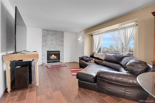 living room with a stone fireplace and a textured ceiling