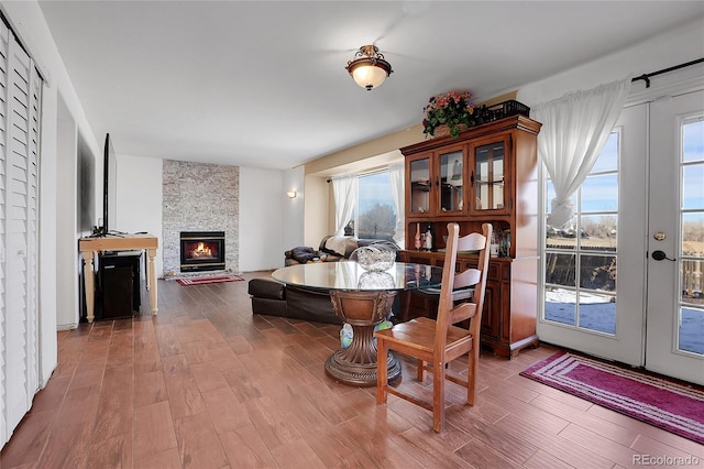 dining space featuring wood-type flooring, a fireplace, and french doors