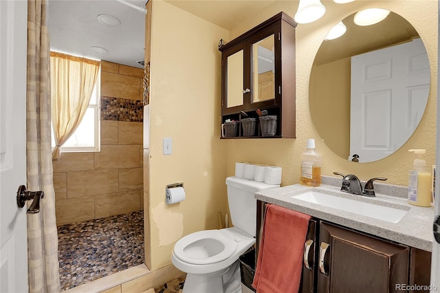 bathroom featuring vanity, toilet, and a tile shower