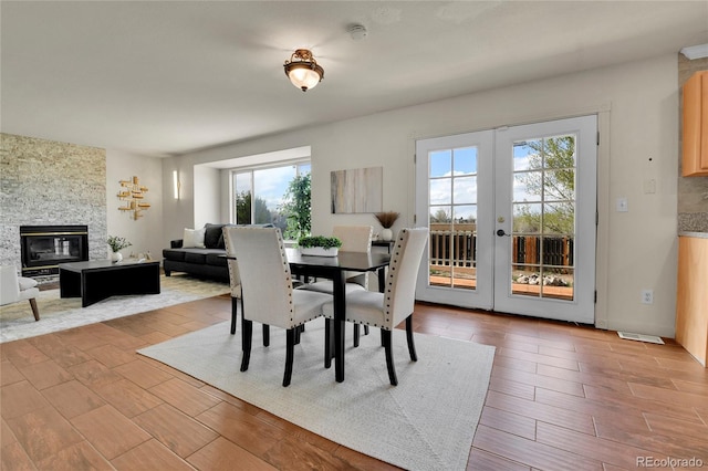 21455 E 44th Ave, Denver, CO 80249 - dining room featuring light wood-type flooring, a fireplace, visible vents, and french doors