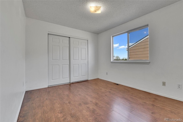 21455 E 44th Ave, Denver, CO 80249 - unfurnished bedroom featuring baseboards, a textured ceiling, wood finished floors, and a closet