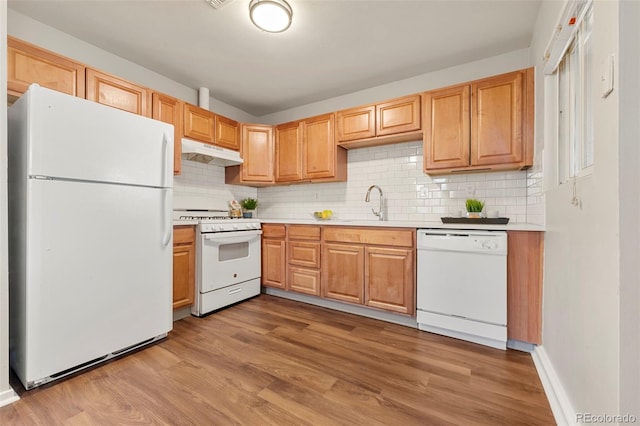 kitchen featuring sink, white appliances, light wood-type flooring, and backsplash