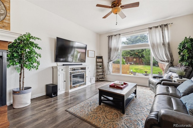 4293 Clover Ln, Brighton, CO 80601 - living area with a glass covered fireplace, a ceiling fan, dark wood-style floors, and baseboards