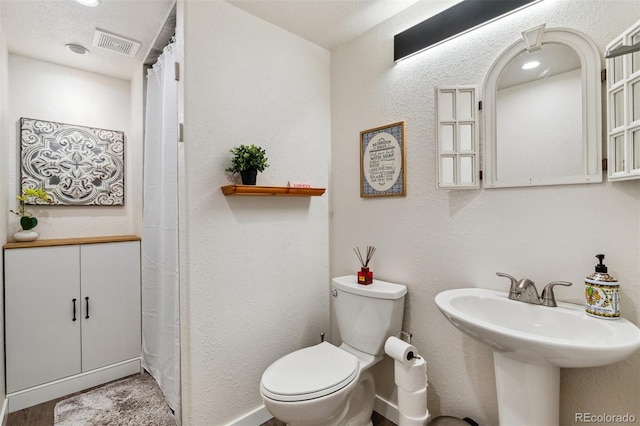 4293 Clover Ln, Brighton, CO 80601 - bathroom with toilet, a textured wall, a sink, and a shower with shower curtain