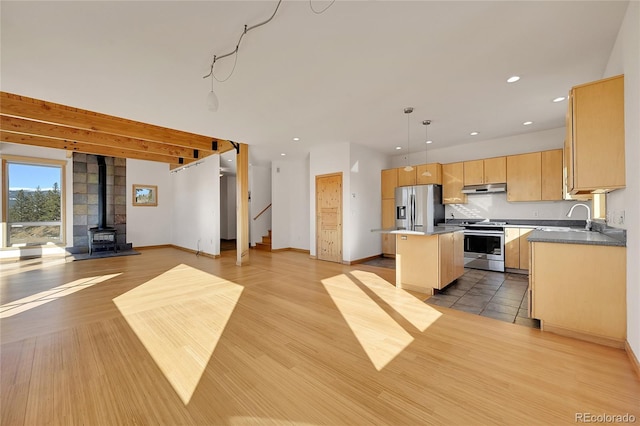 kitchen with appliances with stainless steel finishes, a kitchen island, sink, hanging light fixtures, and light wood-type flooring