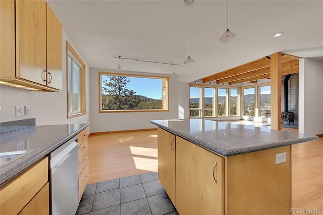 kitchen with a wood stove, light brown cabinets, track lighting, dishwasher, and hanging light fixtures