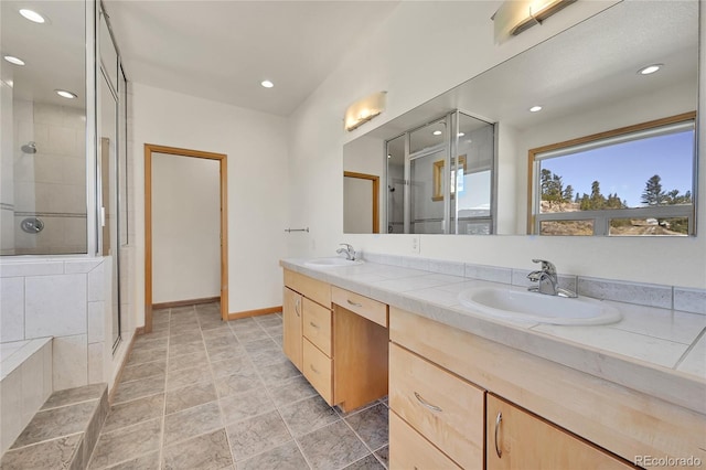 bathroom featuring a shower with shower door and vanity