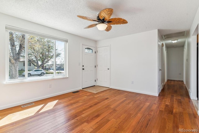 entryway with baseboards, wood-type flooring, a textured ceiling, and visible vents