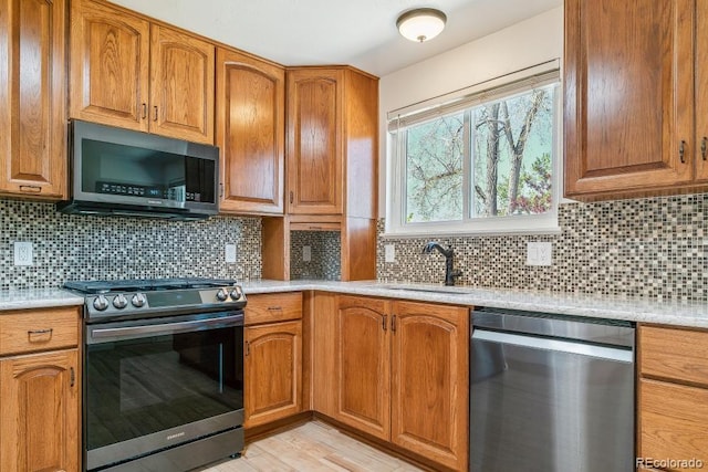 kitchen featuring a sink, light countertops, decorative backsplash, and stainless steel appliances