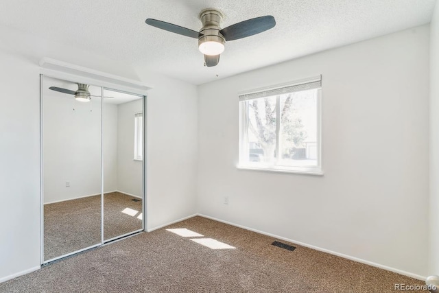 unfurnished bedroom featuring ceiling fan, visible vents, carpet, and a closet