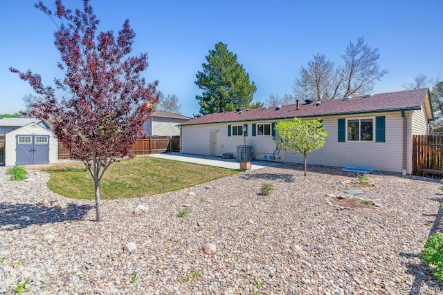 ranch-style home featuring an outdoor structure, a front yard, a fenced backyard, a storage unit, and a patio area