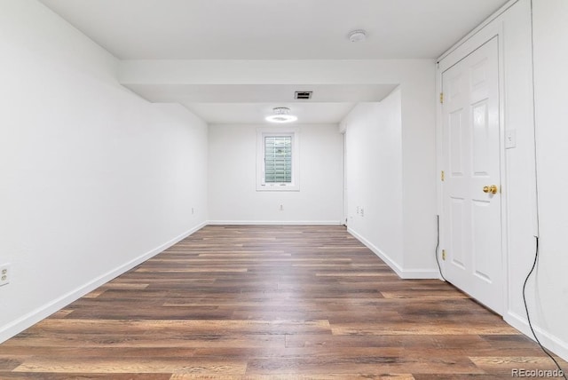 unfurnished room with dark wood-style flooring, baseboards, and visible vents