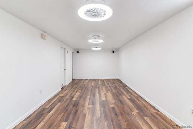 spare room featuring baseboards and dark wood finished floors