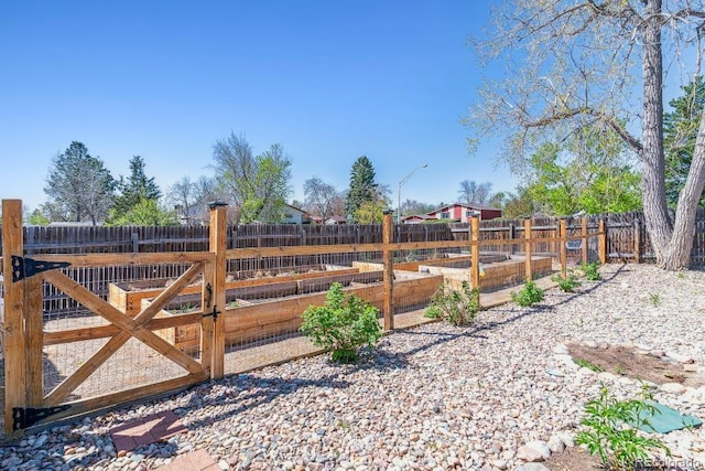 view of gate featuring a vegetable garden and a fenced backyard