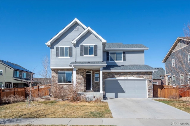 view of front of home with a front yard, fence, an attached garage, concrete driveway, and stone siding