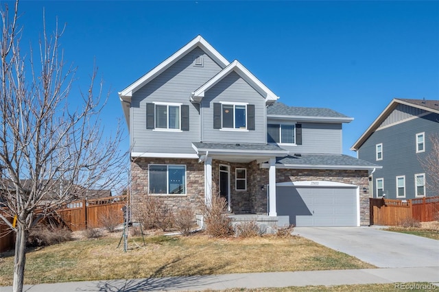 view of front of property with a front yard, fence, driveway, an attached garage, and stone siding